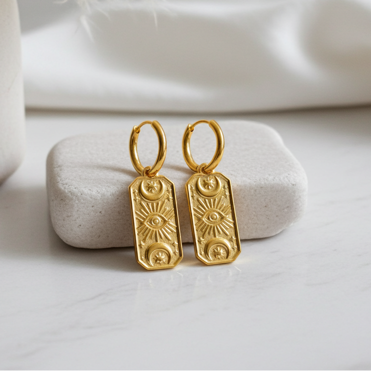 Gold earrings on a white stone with a soft background