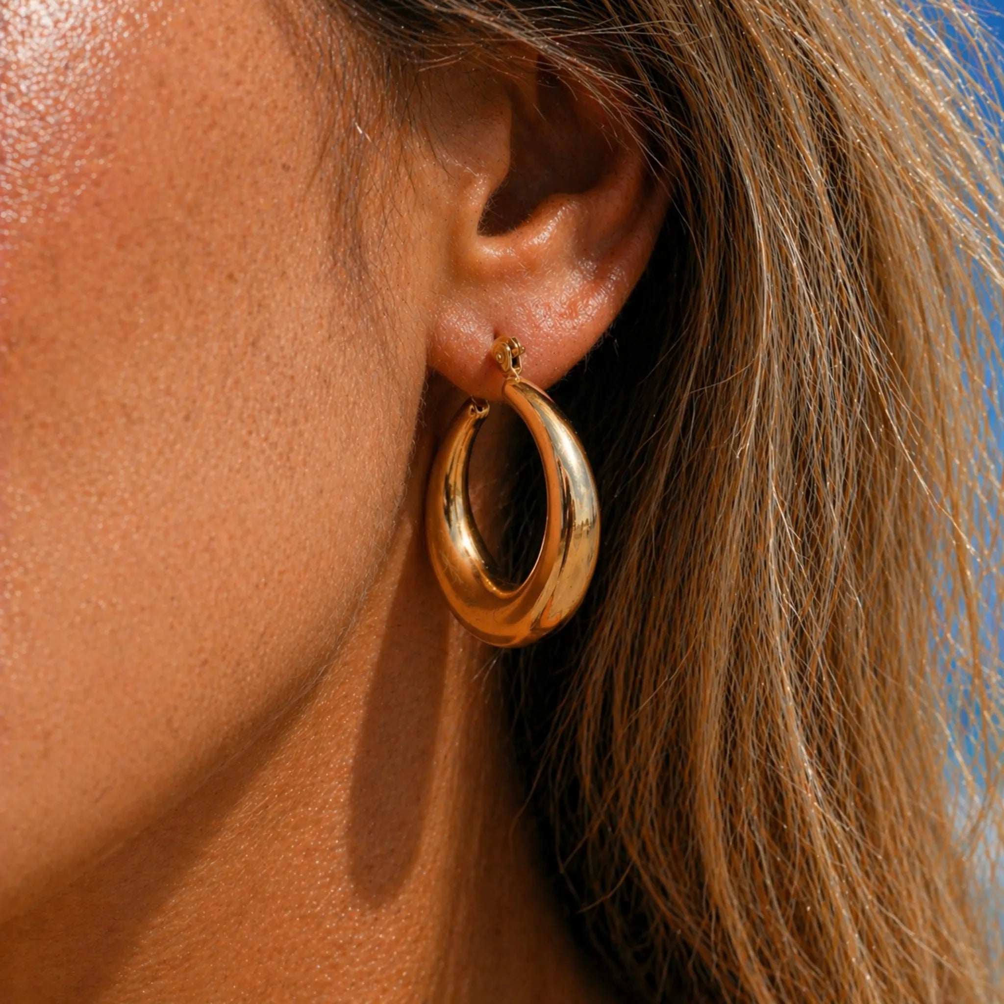 close up of woman wearing a stainless steel chunky gold waterproof hoop earring