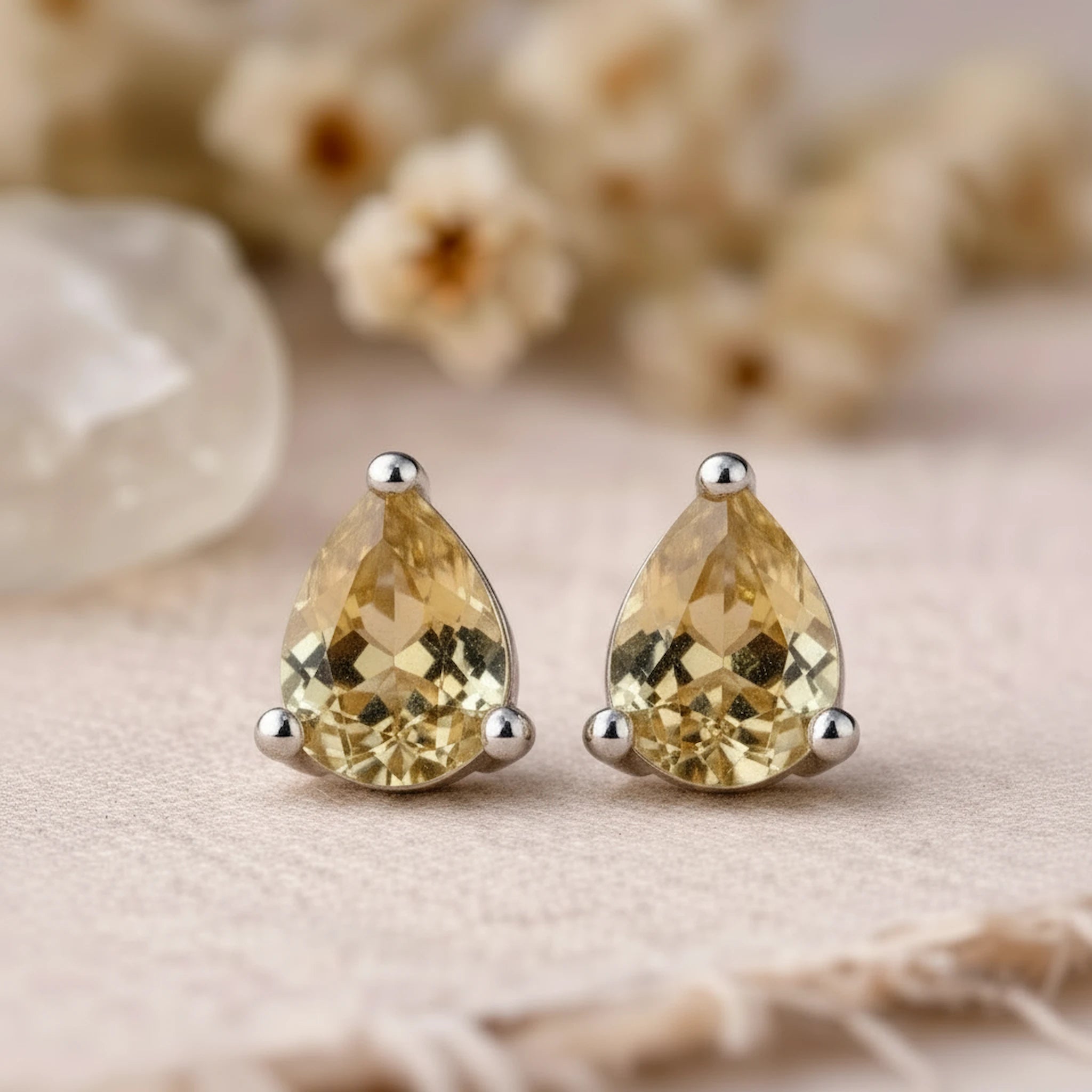 Teardrop-shaped yellow citrine gemstone earrings on a neutral background