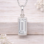 Silver pendant with rectangular gemstone on a light wooden background