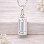 Silver waterproof necklace pendant with rectangular gemstone on a light wooden background
