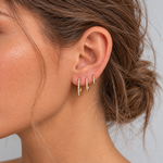 Model with tousled hair wearing three slim gold CZ pavé huggie hoops in 6 mm, 8 mm and 10 mm sizes
