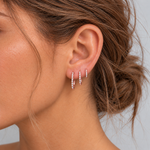 Model wearing three slim rose gold CZ pavé huggie hoop earrings in 6 mm, 8 mm and 10 mm sizes