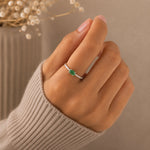Classic Sterling Silver Pave Stacking ring with a oval faceted claw set emerald gemstone worn on a hand with a beige background.