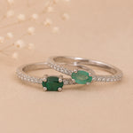 Two Classic Sterling Silver Pave Stacking rings with a oval faceted claw set emerald gemstones on a beige background.