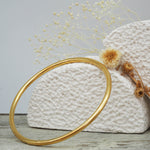 Thin gold bangle made with 18k plated over stainless steel