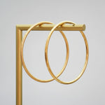 two gold bangle bracelets hanging from a metal rod