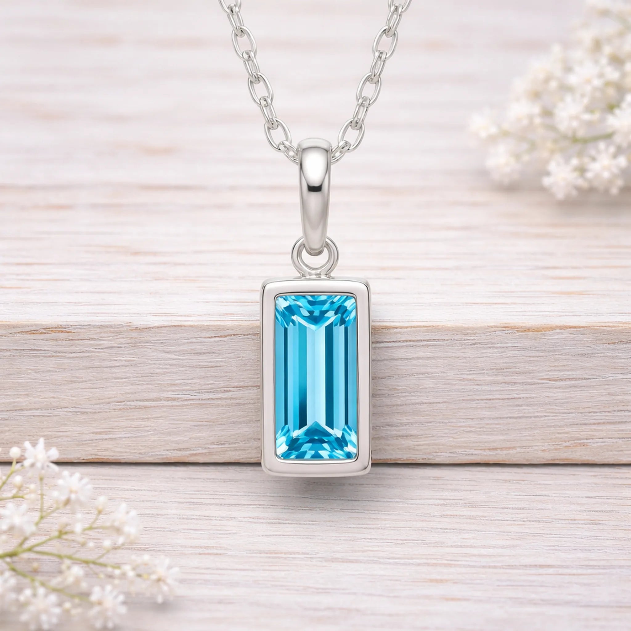 Silver waterproof necklace with a blue gemstone pendant on a light wooden surface.