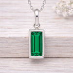 Silver necklace with a green gemstone pendant on a wooden surface