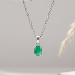 Silver necklace with a green emerald gemstone pendant on a light gray background
