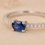 close up macro image of a Sterling Silver pave stacking ring with a oval faceted claw set centre sapphire gemstone on a beige background