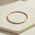 Rose gold bangle on a light beige surface