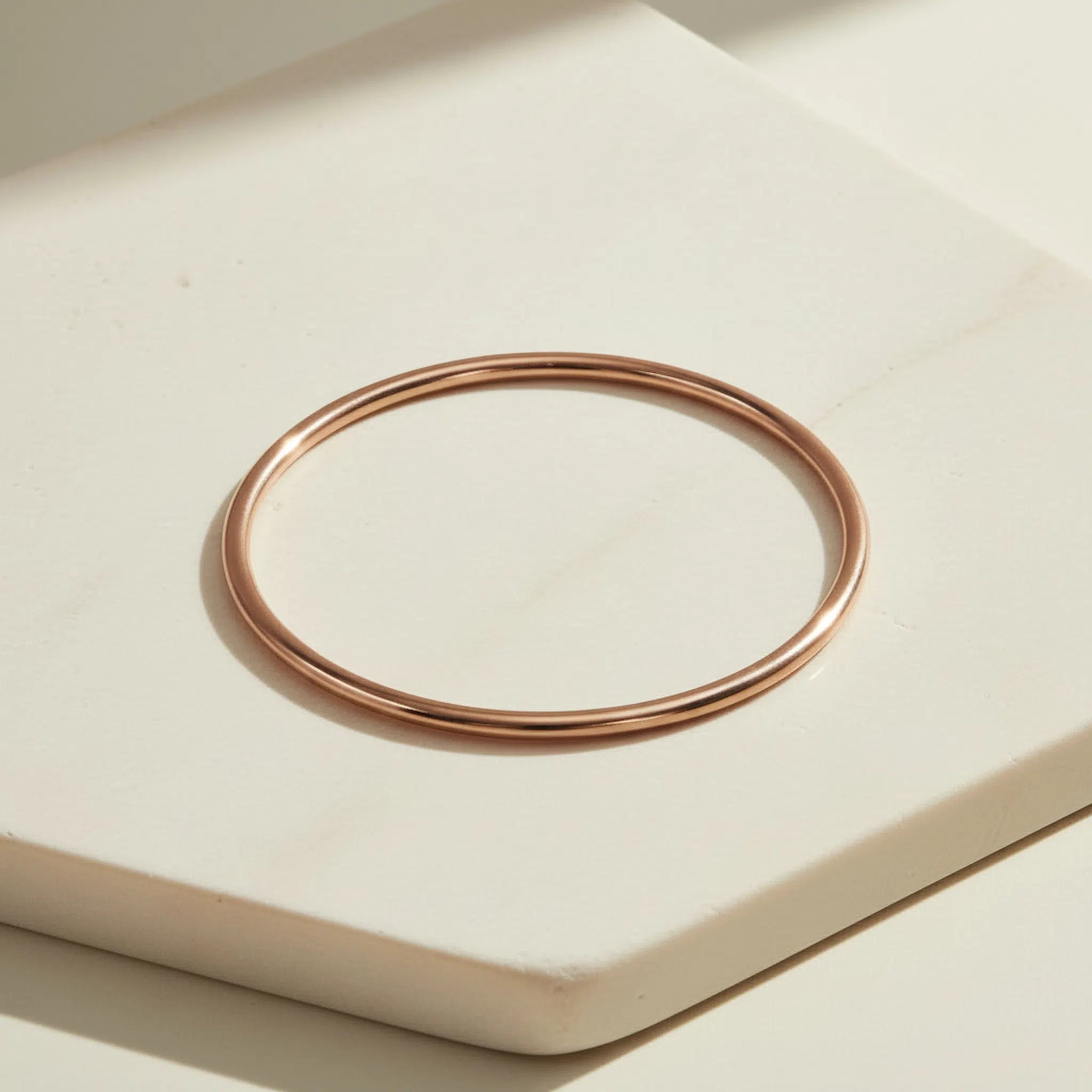 Rose gold bangle on a light beige surface