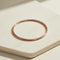 Rose gold bangle on a light beige surface