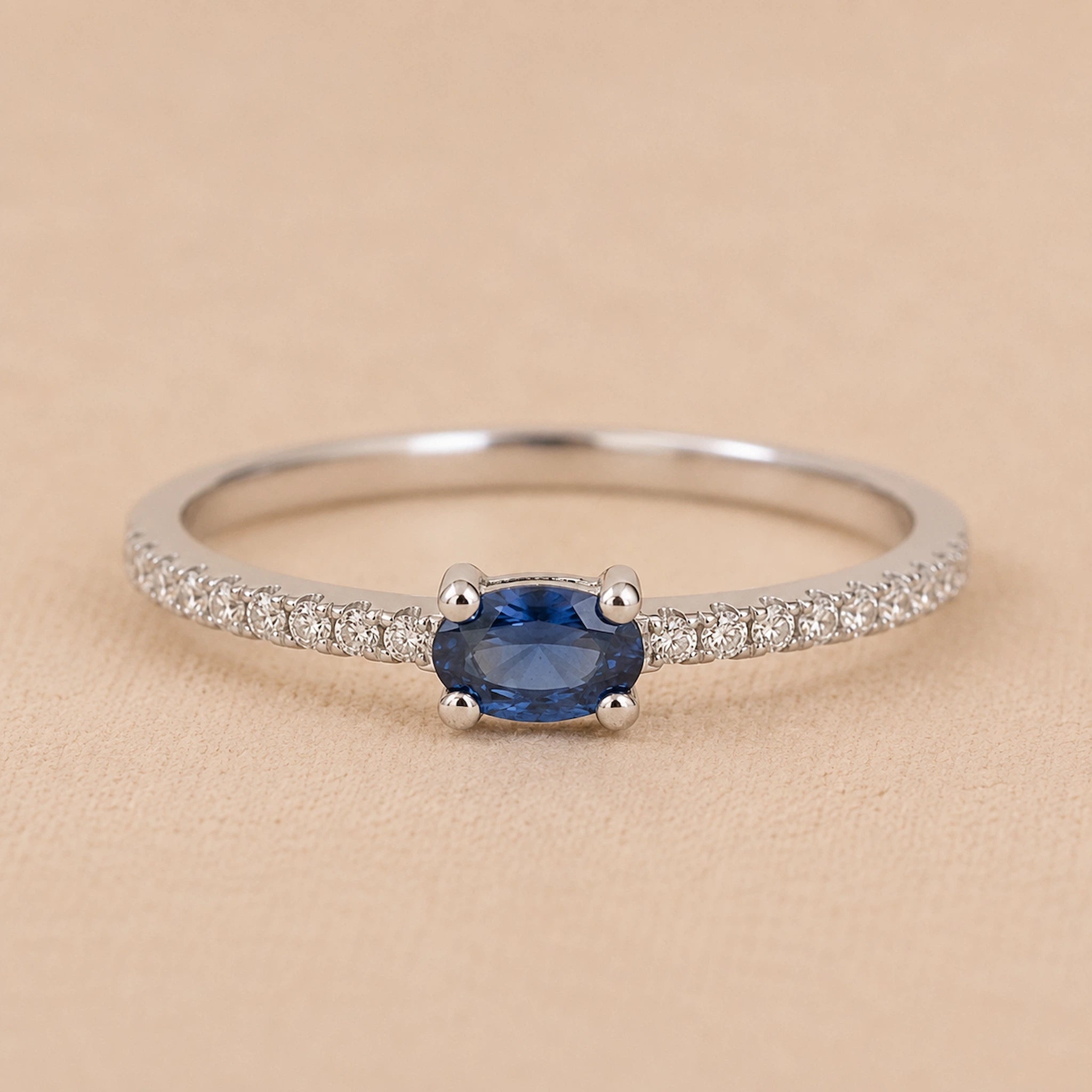 Sterling Silver pave stacking ring with a oval faceted  claw set centre sapphire gemstone on a beige background