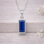 Silver waterproof necklace with a blue gemstone pendant on a wooden surface.
