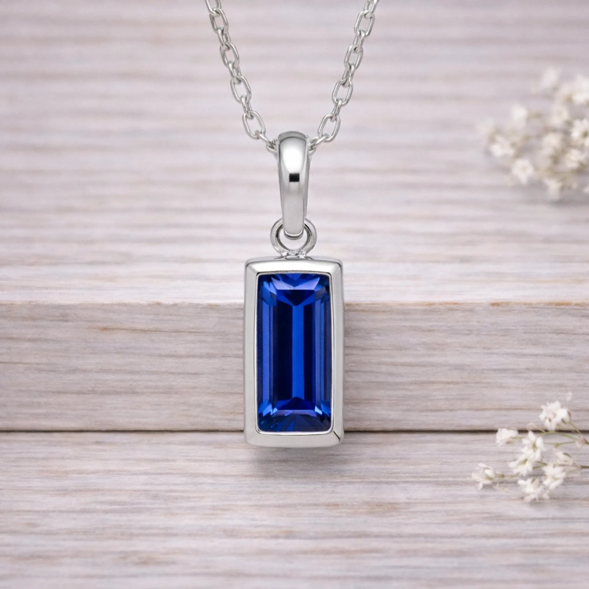 Silver waterproof necklace with a blue gemstone pendant on a wooden surface.