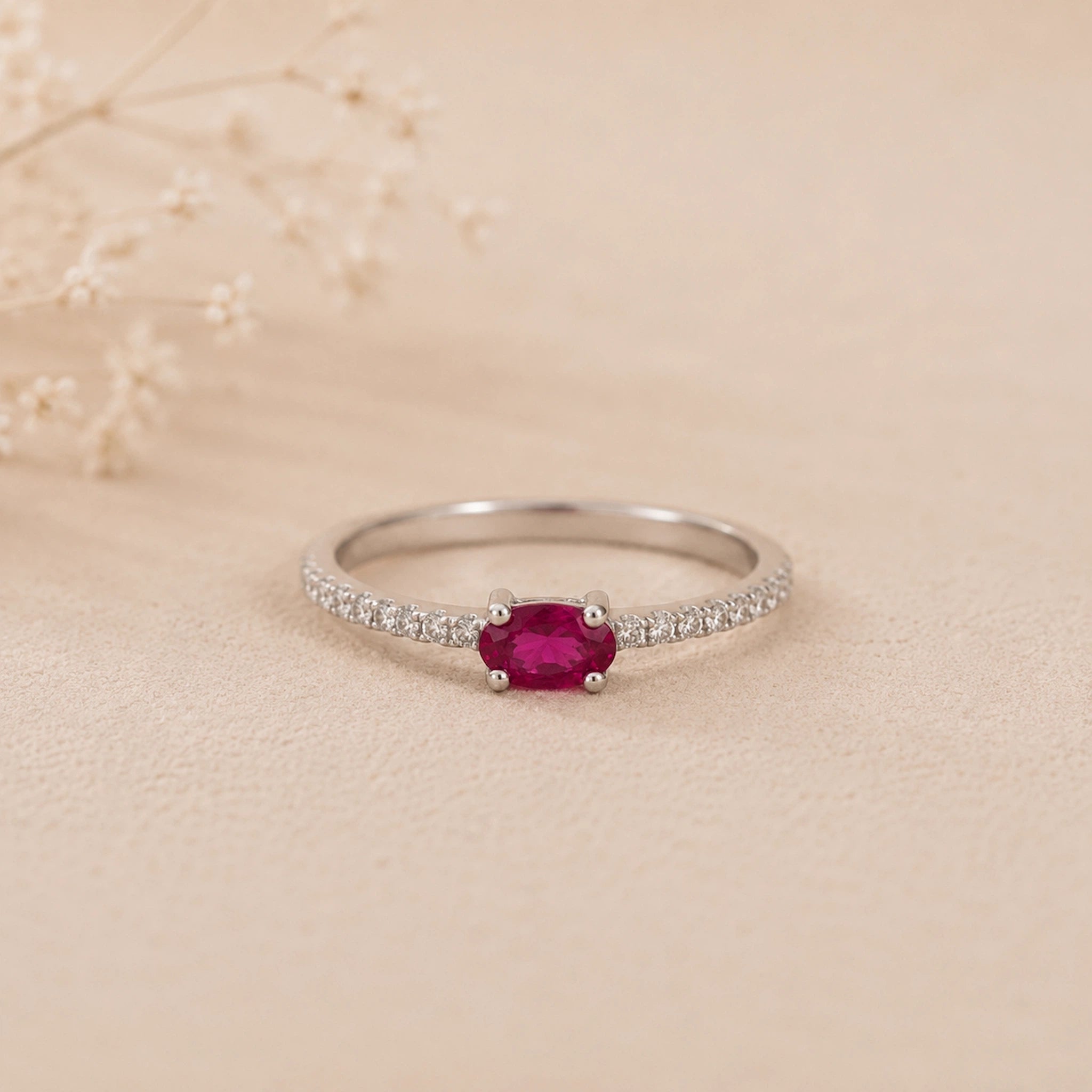 sterling Silver cubic zirconia pave style stacking ring with a red ruby gemstone on a beige background