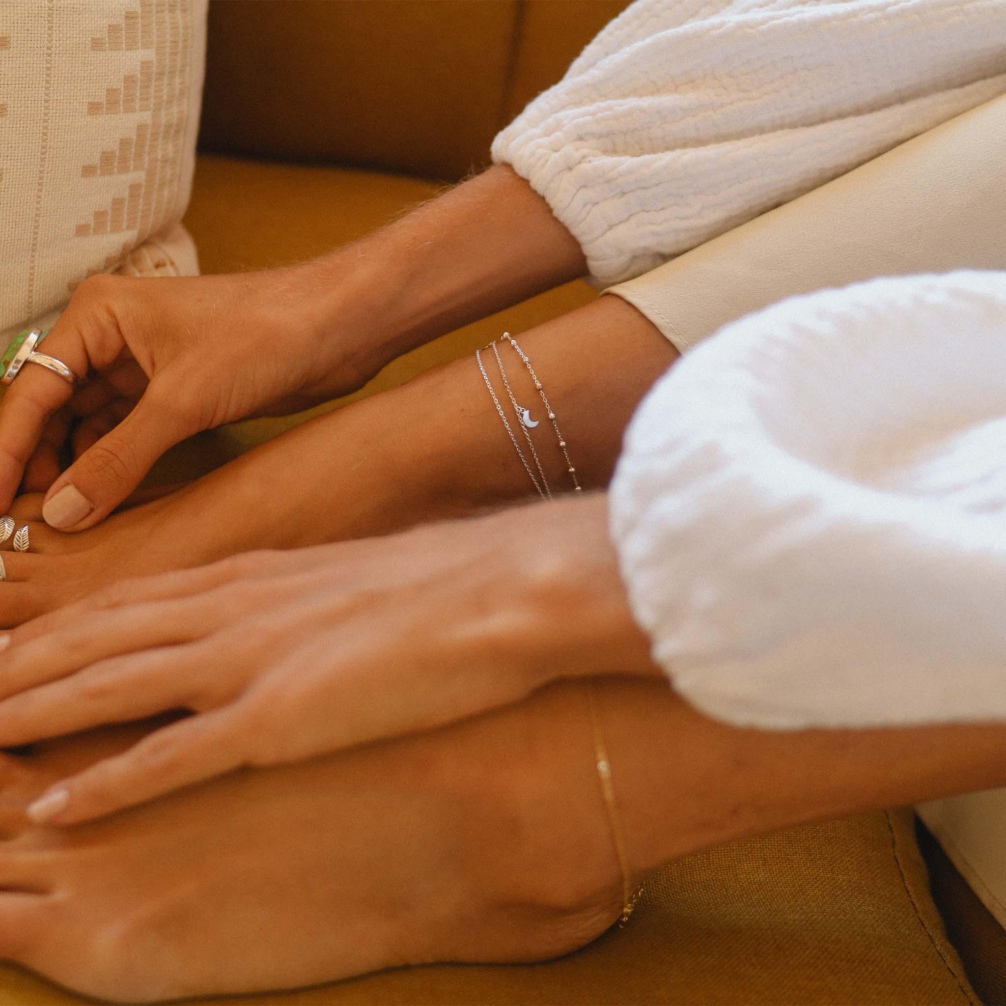 Woman wearing white and wearing a Sterling Silver Anklet with dainty crescent moons