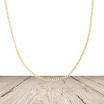 Gold plated sterling silver curb chain necklace on a wooden surface