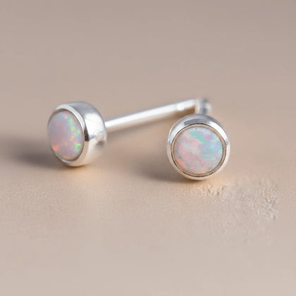 Australia Opal stud earrings with sterling silver setting on a beige background
