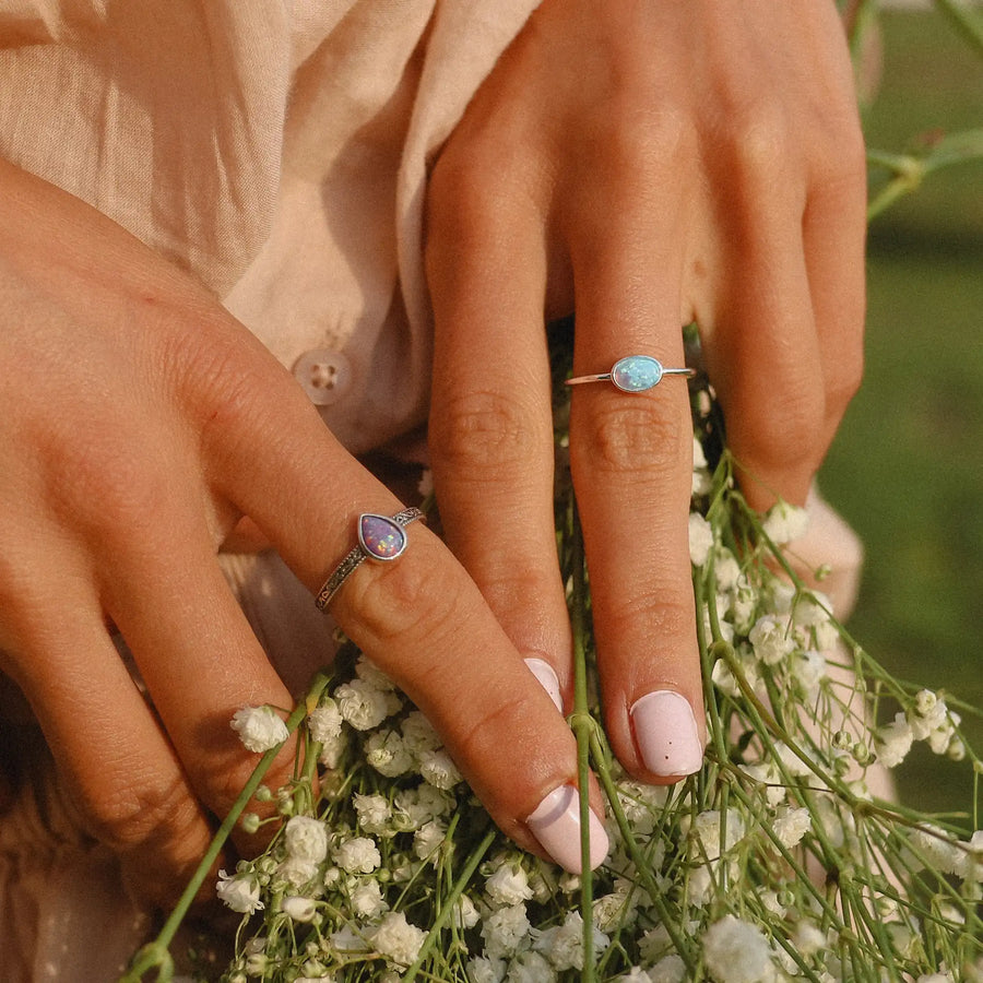 woman holding baby's breath flowers with two sterling silver rings on. one with a blue opal and the other with a purple opal - womens opal jewellery australia