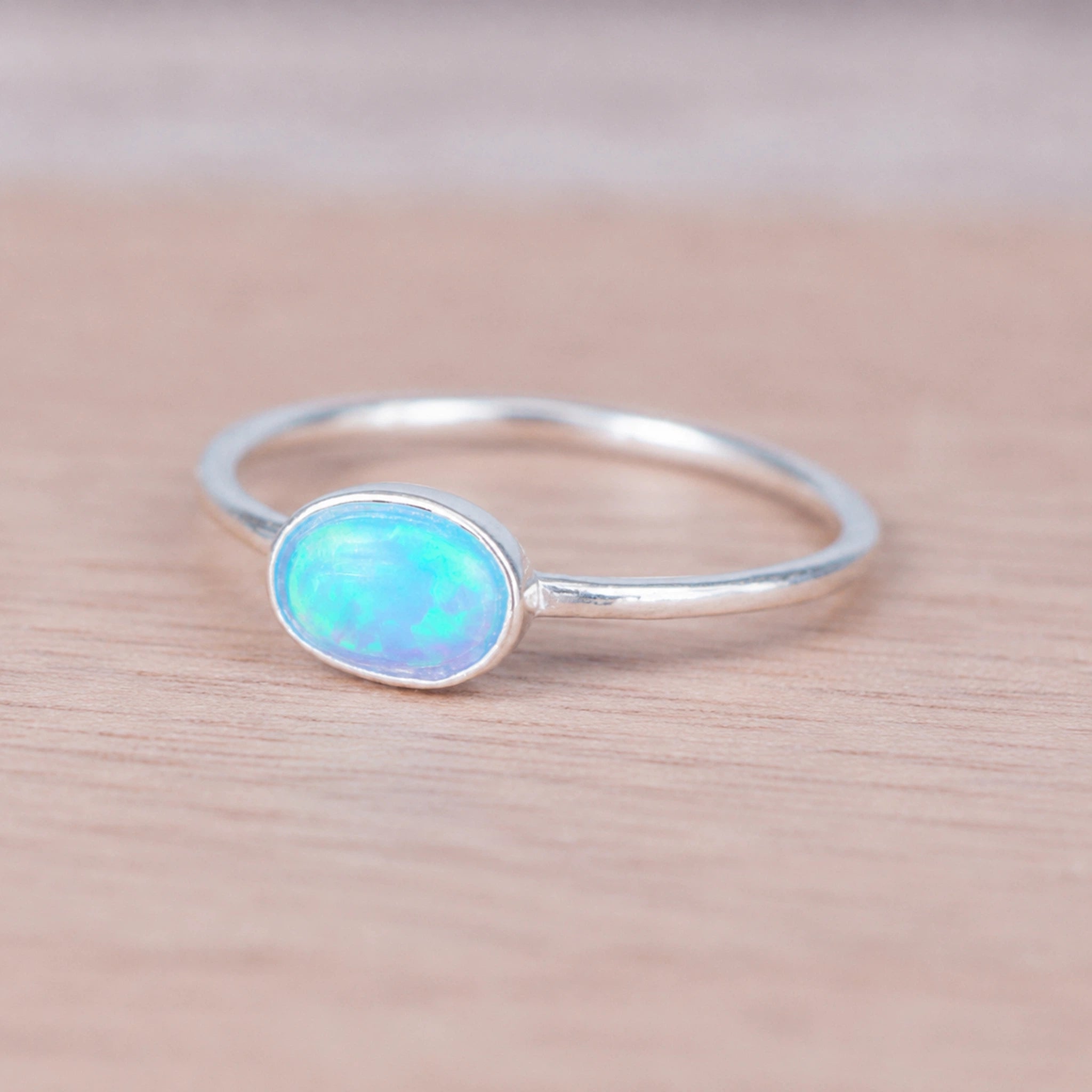 Silver ring with an blue opal stone on a wooden surface