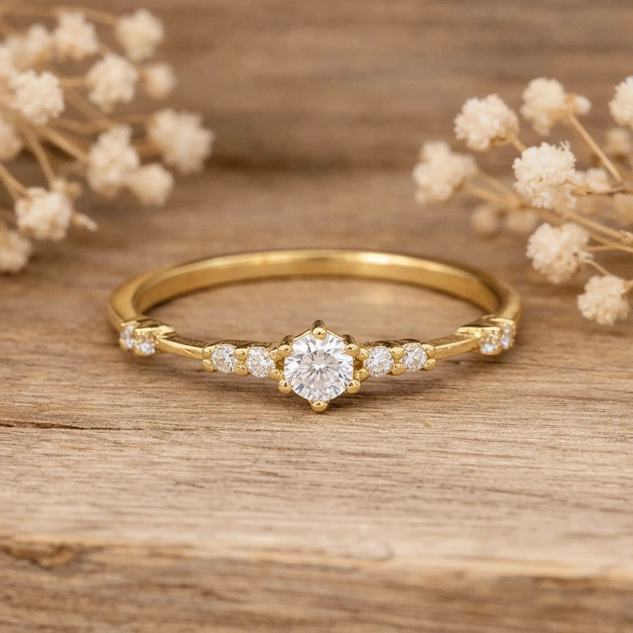 Gold ring with czs on a wooden surface with dried flowers