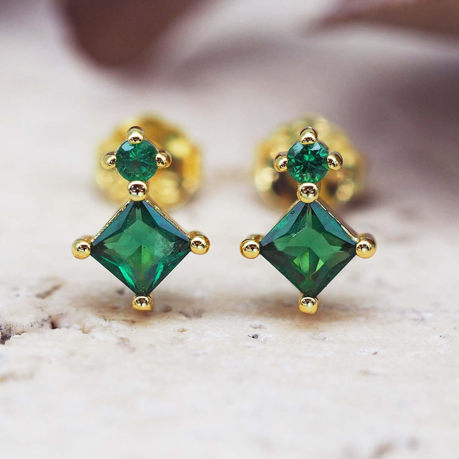 dainty gold earrings with two green crystals