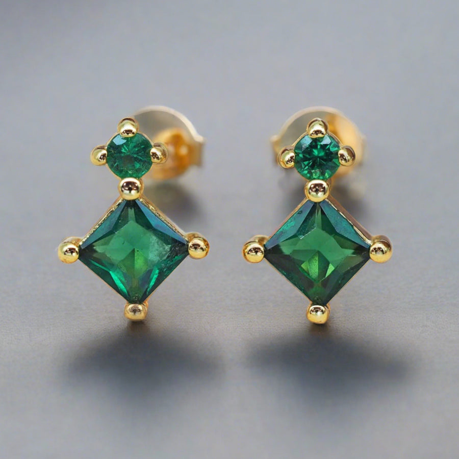 dainty gold earrings with two green crystals