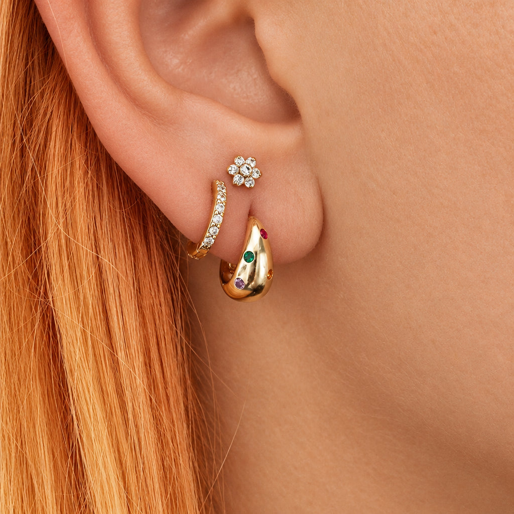 Gold and silver flower helix flat back studs on a grey surface