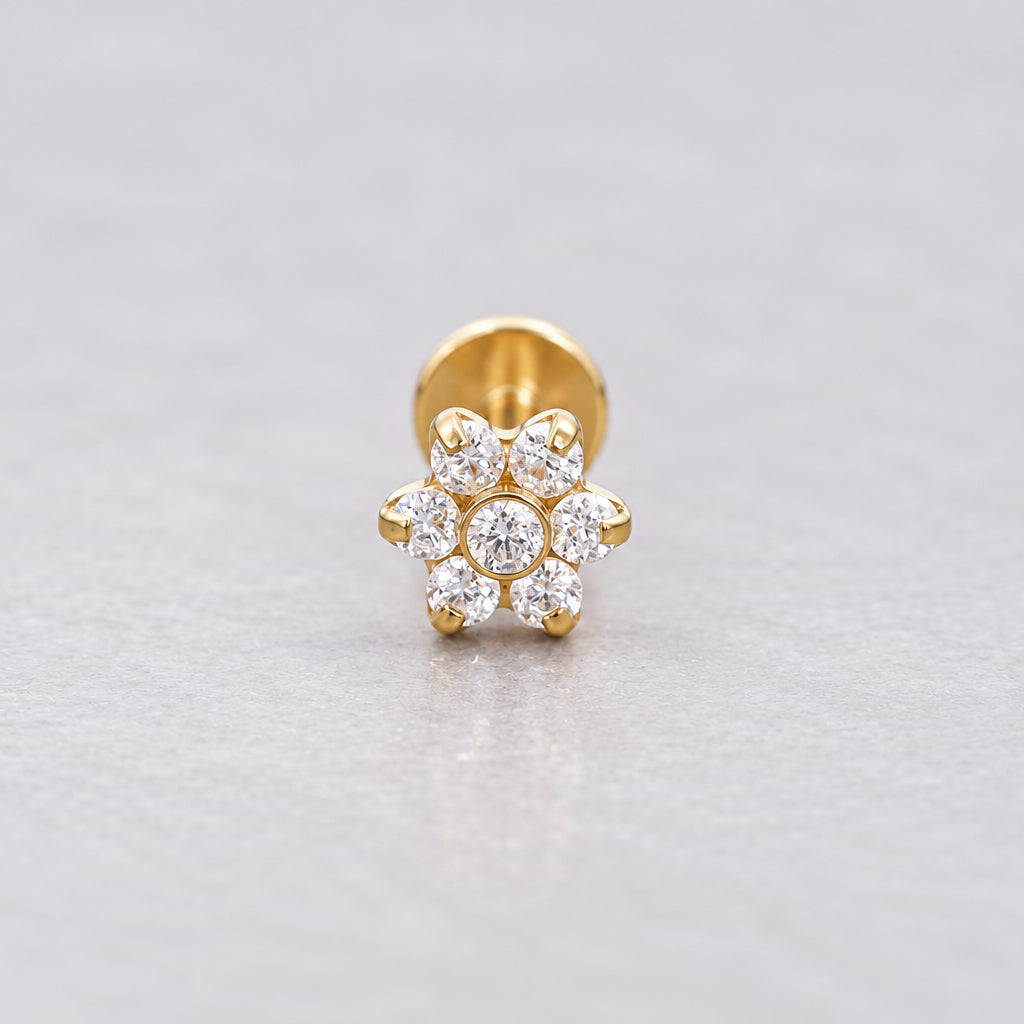 Gold flower flat back earring with cubic zirconia on a grey surface