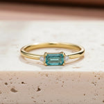 Dainty gold plated sterling silver gemstone ring with rectangular blue green tourmaline centre stone, round cubic zirconia side accents, and slim polished stackable band