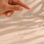 hand holding a dainty gold chain necklace