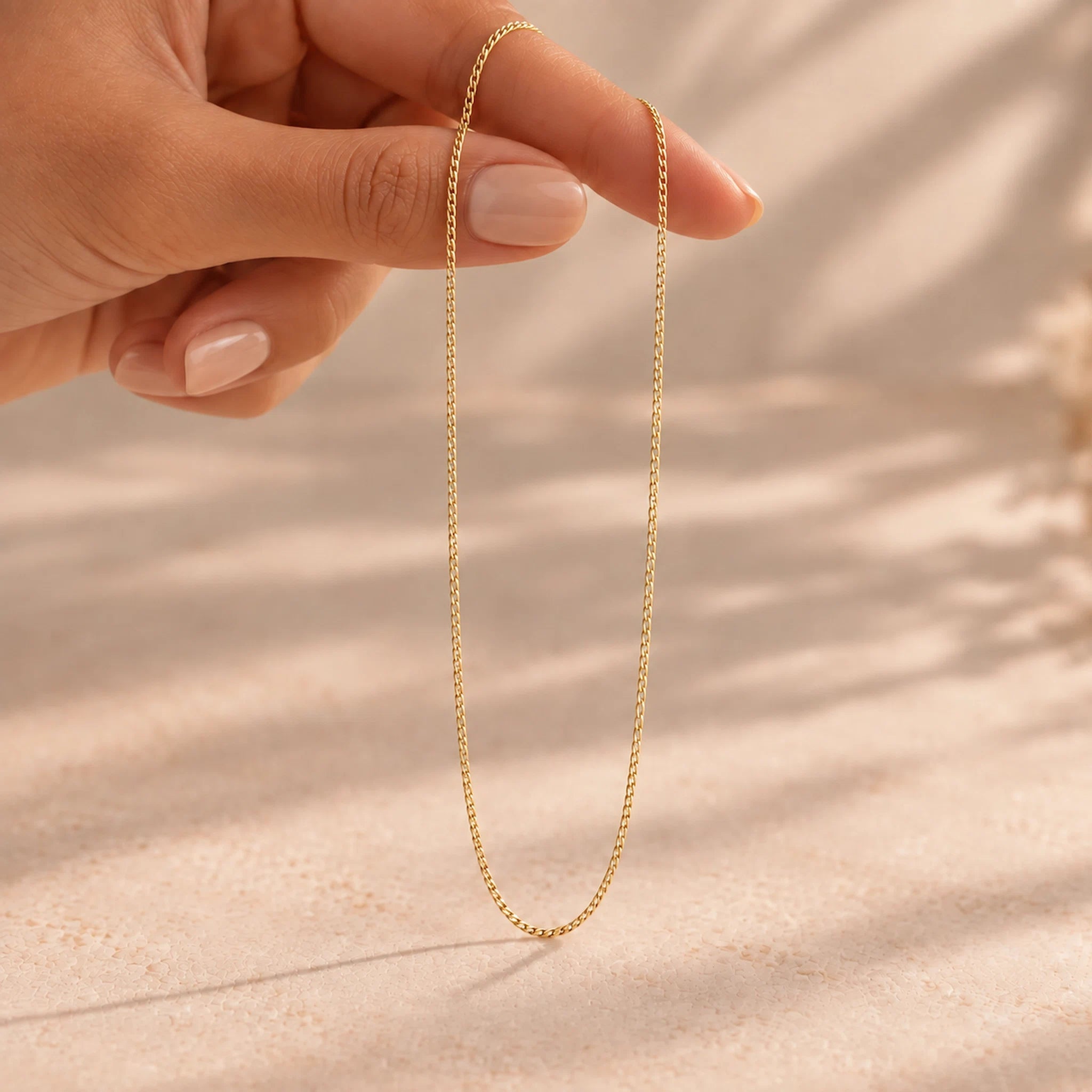 hand holding a dainty gold chain necklace