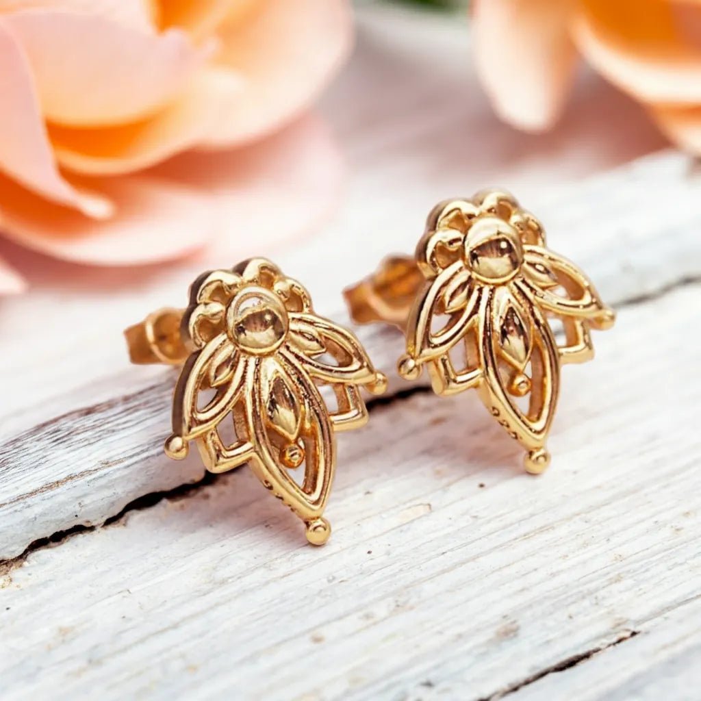 gold dainty lotus flower stud earrings on a piece of wood by indie and harper australia