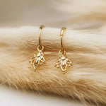 Gold lotus hoop earrings on a fur surface