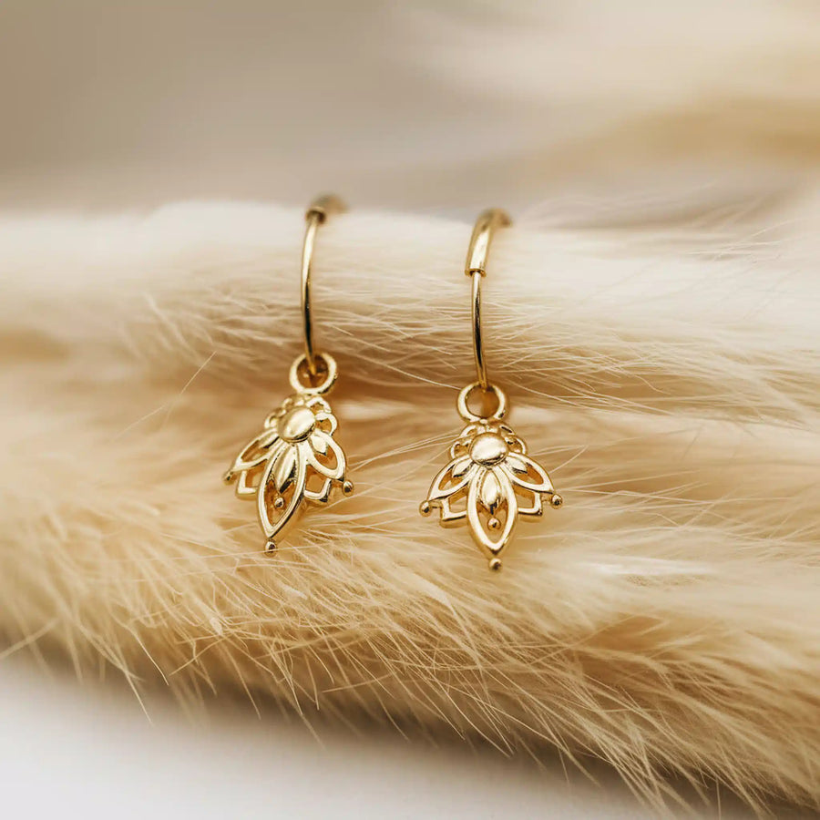 Gold lotus hoop earrings on a fur surface