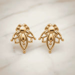 dainty gold lotus flower stud earrings on a light surface