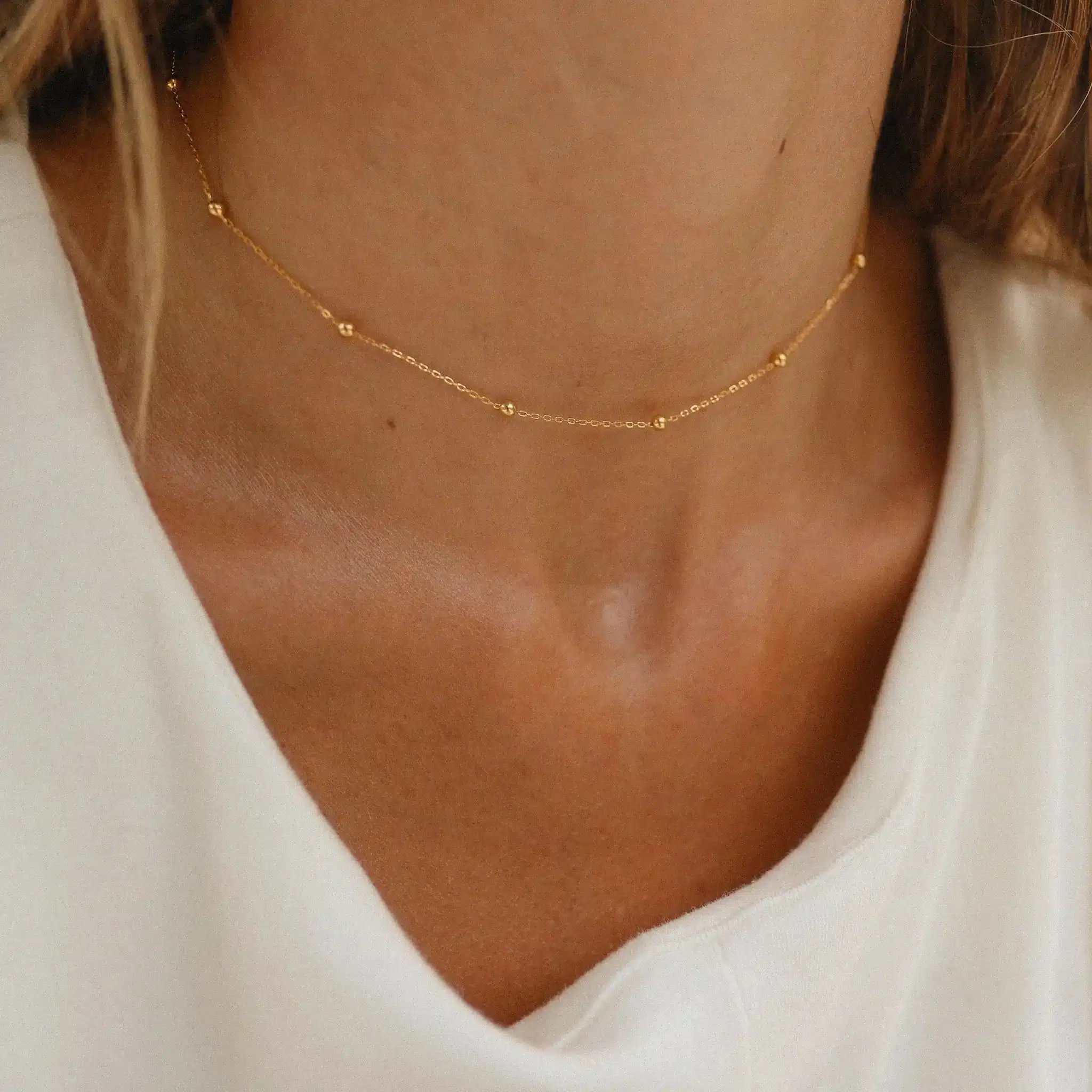 Woman wearing the gold dainty beaded chain necklace