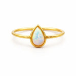 Gold ring with a teardrop-shaped opal stone on a white background