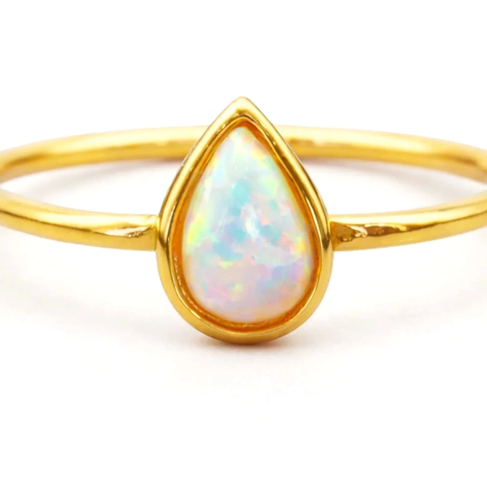Gold ring with a teardrop-shaped opal stone on a white background