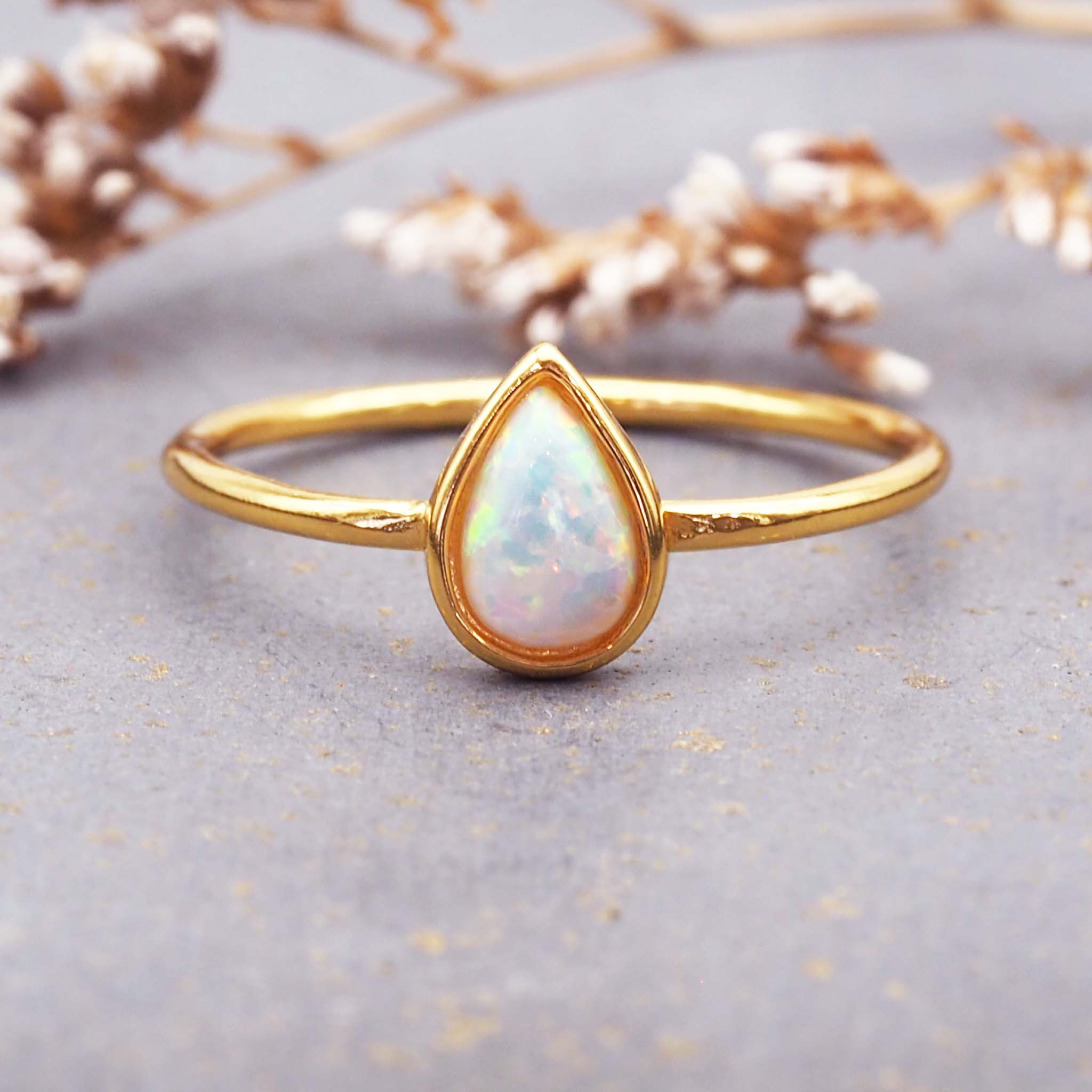Gold ring with a teardrop-shaped opal stone on a gray background