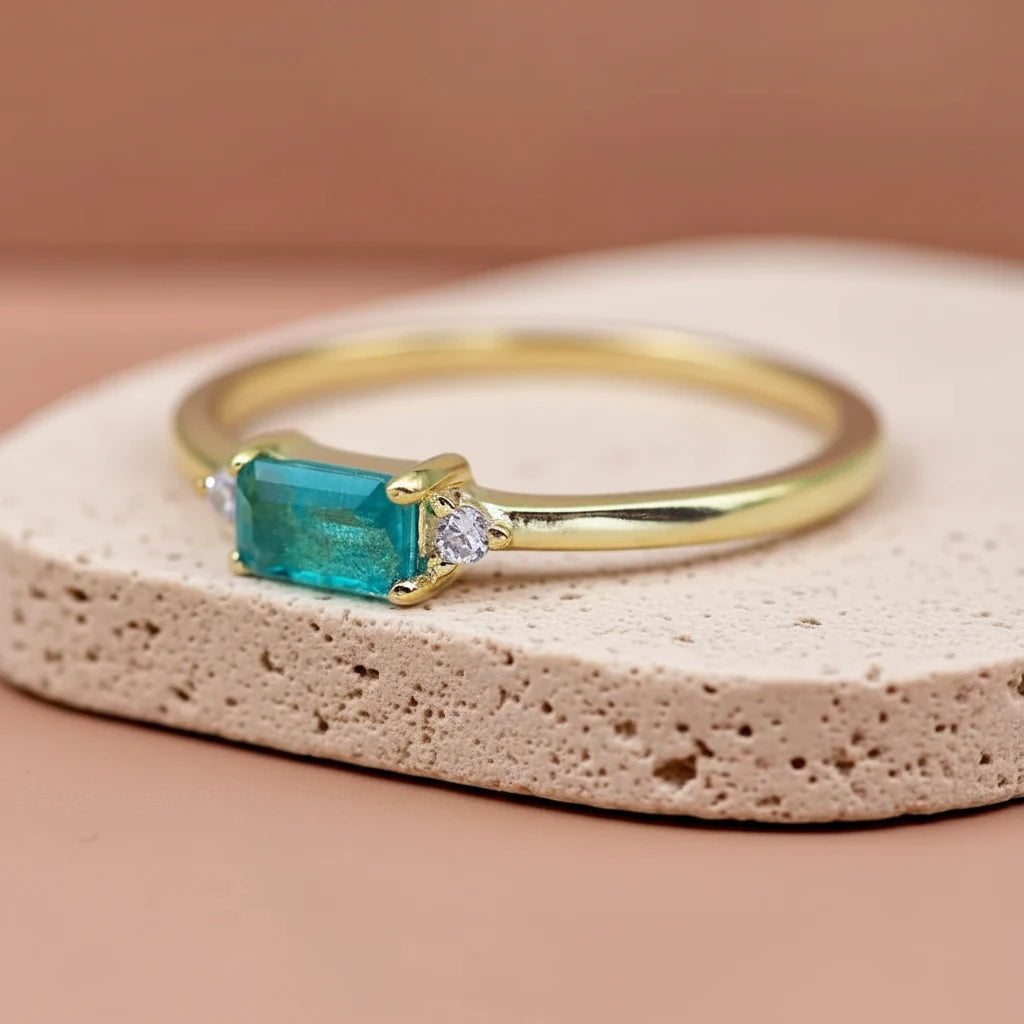 Dainty gold plated sterling silver gemstone ring with rectangular blue green tourmaline centre stone, round cubic zirconia side accents, and slim polished stackable band
