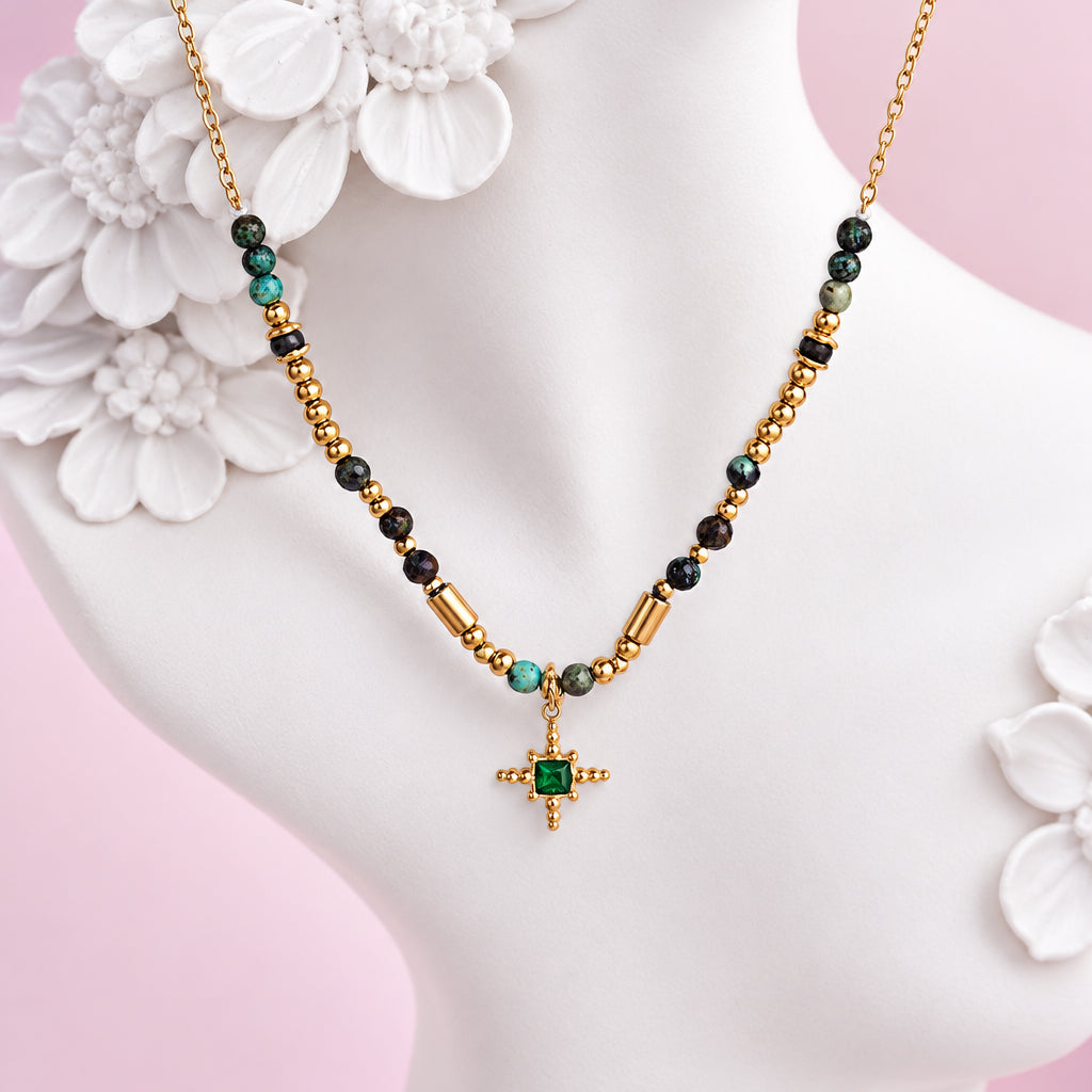 Gold turquoise beaded necklace on a white ceramic bust with flowers and a pink background