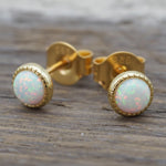 Gold White Opal stud earrings on a wood background