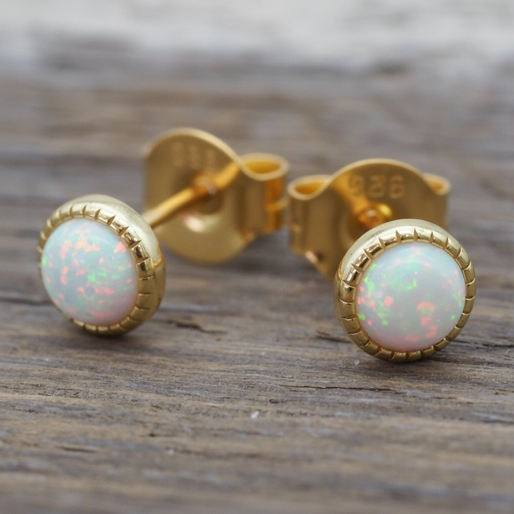 Gold earrings with opal stones on a wooden surface