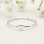 dainty sterling silver heart ring on a wooden surface
