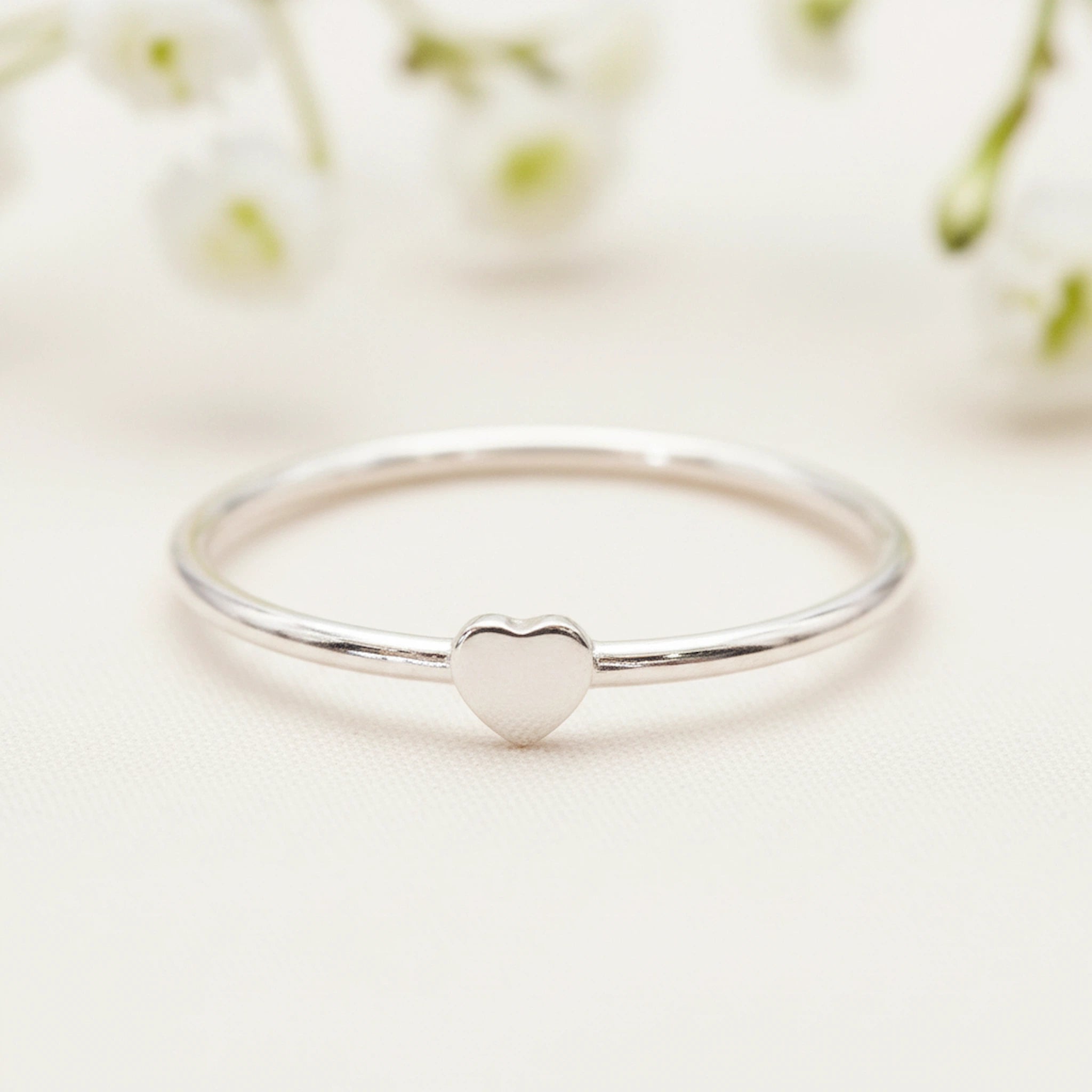 dainty sterling silver heart ring on a wooden surface