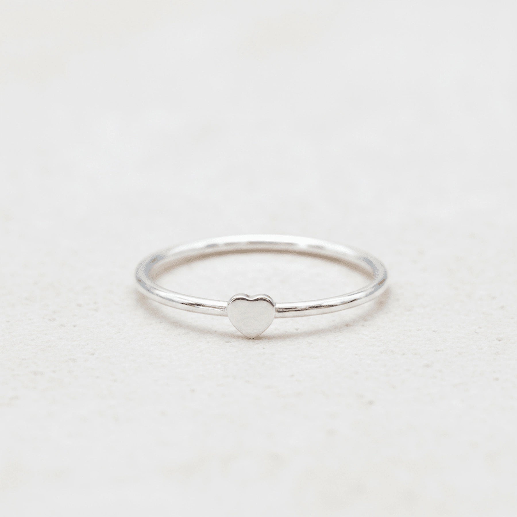 Silver ring with a heart-shaped design on a light background
